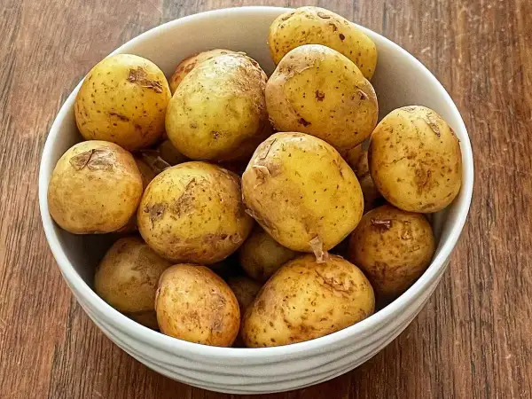 En skål med färskpotatis, redo att koka med eller utan lock. Perfekt för en svensk sommarmåltid.