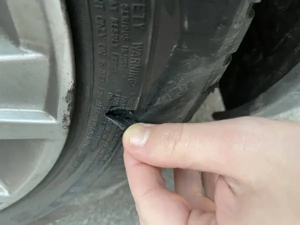 Un pneu abîmé sur le flanc, probablement suite à un choc contre le trottoir. La gomme est déchirée.