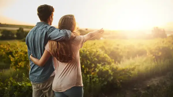 Coppia abbracciata al tramonto in un campo, un momento di serenità che ispira a capire come abbassare la pressione in modo naturale.