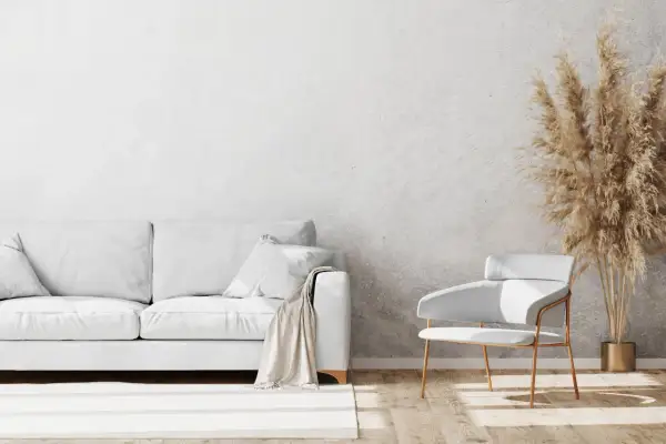 Un salon moderne avec un canapé blanc, un fauteuil design et un bouquet de pampas sur un mur au motif crépis.