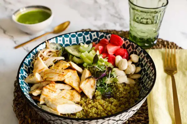 Una ciotola colorata con pollo grigliato, verdure fresche, fragole e mandorle su un letto di cous cous. Perfetta per le tue ricette con il cous cous.