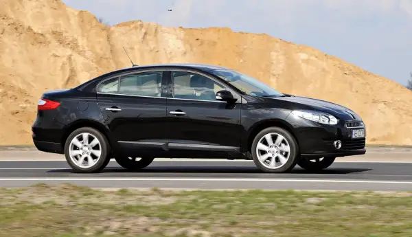 Czarny Renault Fluence jedzie po drodze, w tle piaszczyste wzgórza.