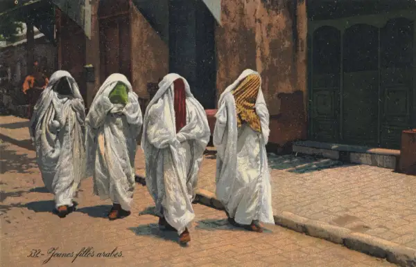 Cztery kobiety w białych, luźnych szatach i welonach, zasłaniających twarze. Czy to burka? Widać fragmenty kolorowych tkanin pod welonami.