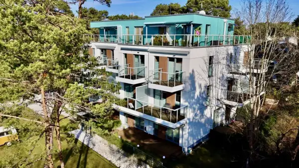 Nowoczesne władysławowo apartamenty przy plaży z widokiem na morze. Balkony z przeszklonymi balustradami i zielone otoczenie.