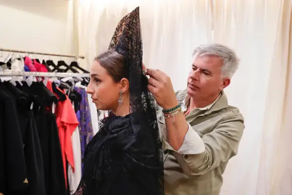 Hombre ayuda a mujer a cómo hacer moño para mantilla, ajustando el velo negro con encaje.