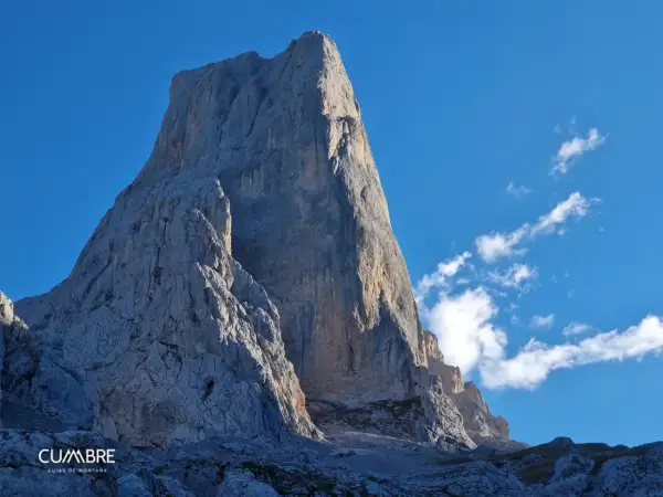 El imponente Urriellu se alza majestuoso bajo un cielo azul, invitando a contemplar el tiempo y la grandeza de la montaña.