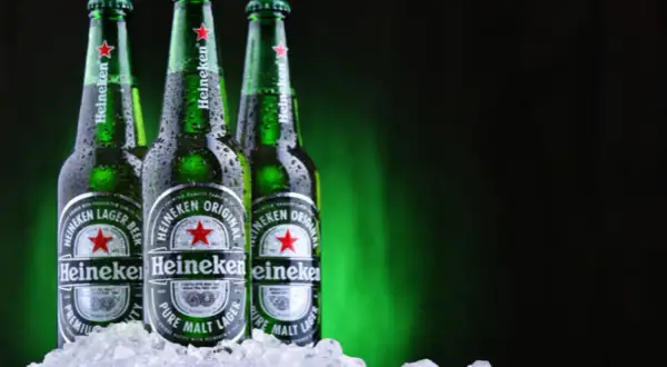 Trzy butelki Heineken, holenderskiej marki piwa, w lodzie.