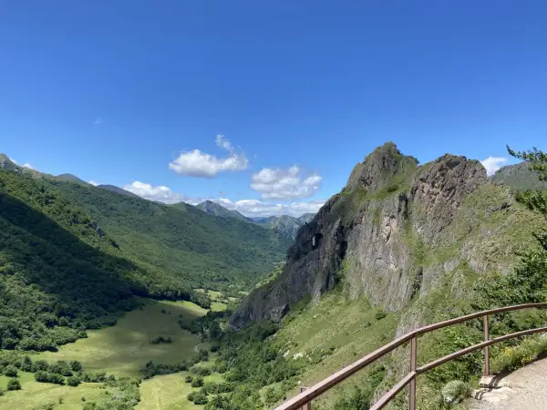 Un valle verde y montañoso con un arco natural en la roca, ideal para rutas circulares en Somiedo.