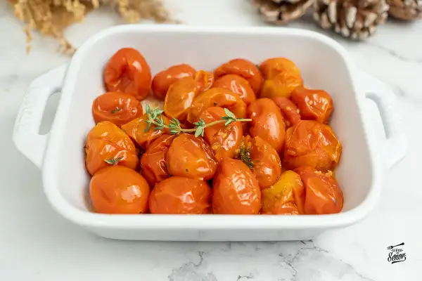 Tomates confitados en una fuente blanca, con ramitas de tomillo fresco. Un plato delicioso y aromático.