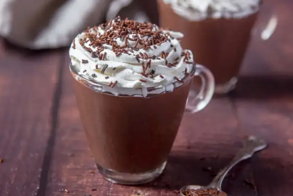 Cioccolata calda con acqua e cacao, guarnita con panna montata e codette di cioccolato. Un comfort food perfetto per riscaldarsi.