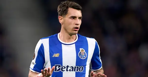 Piłkarz FC Porto, gdzie gra Kiwior, w niebiesko-białej koszulce, z uwagą obserwuje grę.