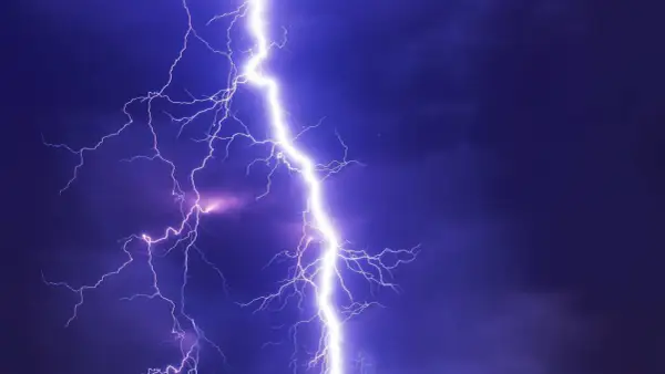 Potężne wyładowanie, przepięcie prądu rozświetla nocne niebo. Błyskawice rozchodzą się niczym gałęzie drzewa.