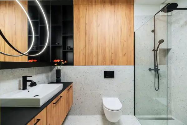 Nowoczesna łazienka inspiracje: drewniane panele, kamień terrazzo, czarna armatura i designerskie oświetlenie tworzą stylową przestrzeń.