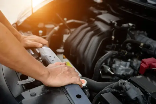 Man checks the engine of a used car, ensuring it's in good condition before purchase.