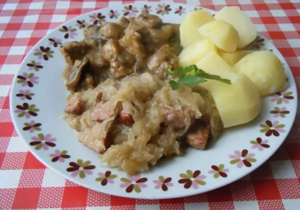 Pyszna kapusta kiszona gotowana z kawałkami mięsa i kiełbasy, podana z ziemniakami.