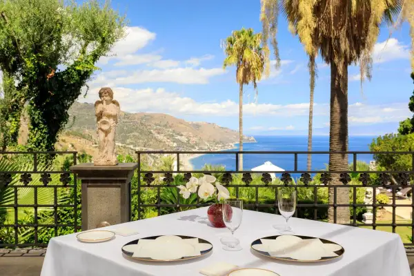 Tavola apparecchiata con vista mare a Taormina, un'esperienza tra i migliori ristoranti.