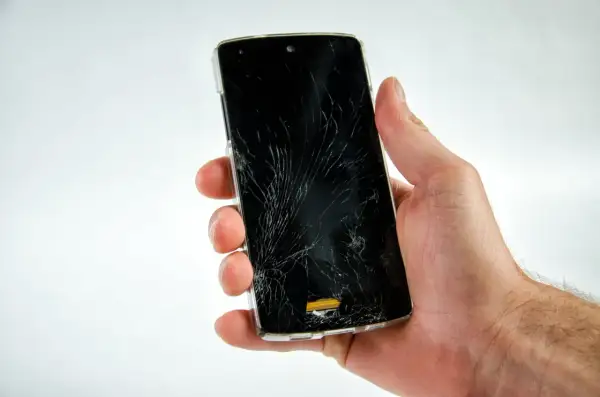 Dłoń trzyma pęknięty telefon, który nie chce się włączyć.