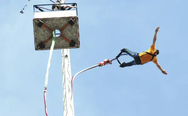 Człowiek w żółtej koszulce skacze na bungee. Zastanawiasz się, ile kosztuje skok na bungee? To niezapomniane przeżycie!