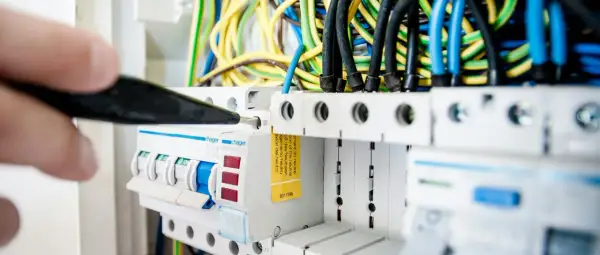 En elektriker arbetar med en elcentral, en viktig del för att kontrollera driftskostnad villa.