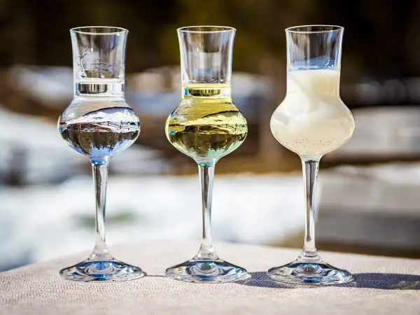 Trzy kieliszki z różnymi alkoholami, w tym grappa. W tle zimowy krajobraz.