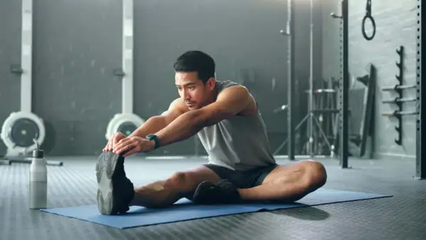 Mann dehnt sich im Fitnessstudio, um den Muskelaufbau zu unterstützen.