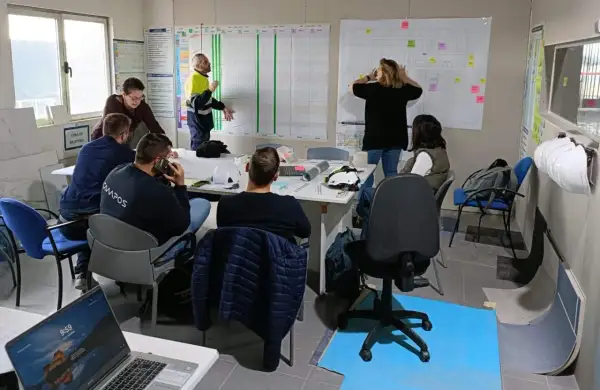 Equipo discutiendo un plan de proyecto en una sala de reuniones, aplicando principios de **lean construction** para optimizar el proceso.