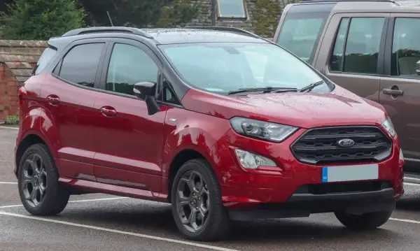 Czerwony Ford EcoSport 2018 z czarnym dachem, zaparkowany na mokrym parkingu.