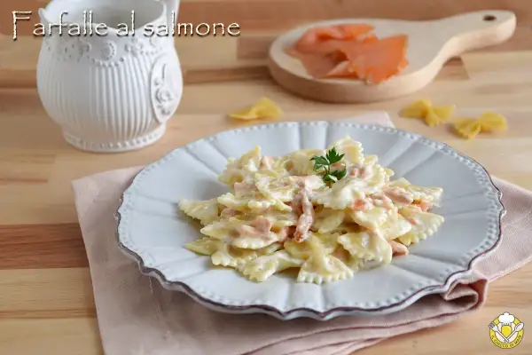 Farfalle al salmone cremose, un piatto invitante con pasta a forma di farfalla e pezzetti di salmone affumicato, guarnito con prezzemolo fresco.
