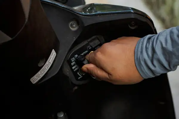 Mano girando la llave de encendido por magneto en una motocicleta.