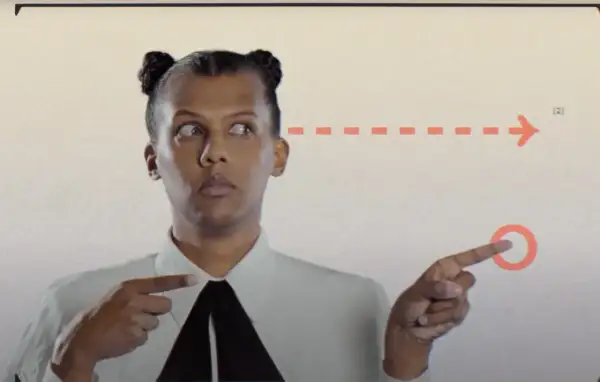 Stromae w Polsce, z charakterystycznymi kucykami, wskazuje na strzałkę.