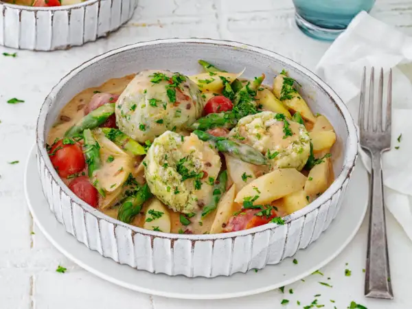 Spargel mal anders: cremiger Eintopf mit Klößen, Kartoffeln, Kirschtomaten und grünen Bohnen, garniert mit Petersilie.