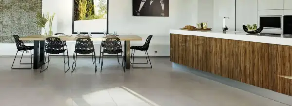Un salon moderne avec une table en bois, des chaises noires design et un îlot de cuisine en bois. Le sol en carrelage clair complète l'ensemble.