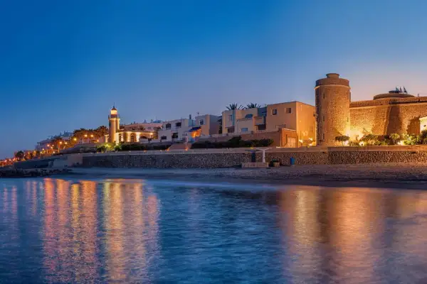 Atardecer en Roquetas de Mar. Faro y castillo iluminados, reflejos en el mar. ¡Ideas de qué hacer en Roquetas de Mar!