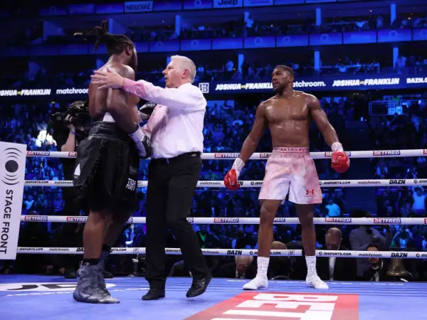 Referee separates boxers after a round. The crowd watches, anticipating how many knockdowns in boxing will occur next.