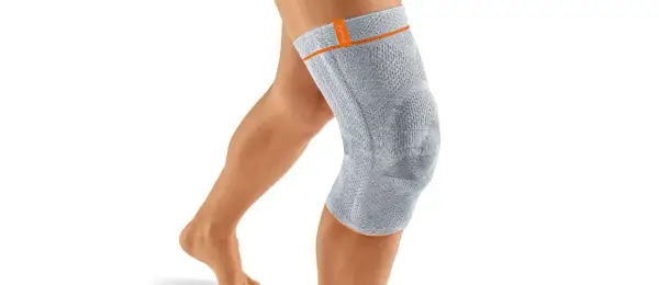 Ein Bein mit einer grauen Kniebandage. Die Bandage könnte bei falscher Anwendung oder zu engem Sitz Schmerzen verursachen.