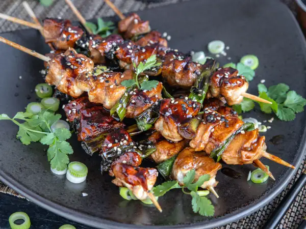 Leckeres Yakitori: saftige Hähnchenspieße mit Teriyaki-Glasur, garniert mit Sesam und Frühlingszwiebeln.
