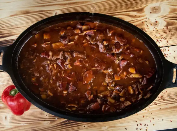 Herzhaftes Gulasch im Dutch Oven, ein Klassiker der Dutch Oven Rezepte. Daneben liegt eine rote Paprika.