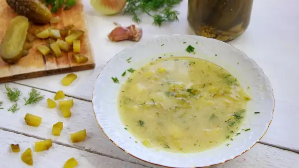 Zupa ogórkowa przepis babci, pachnąca koperkiem i czosnkiem, z kawałkami ogórków na desce i w słoiku.