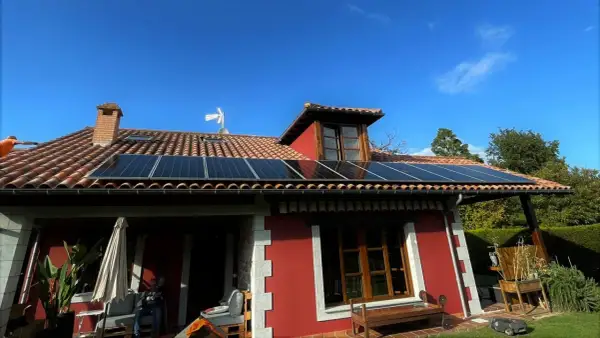 Instalación de placas solares en tejado rojo de casa en Asturias. Aprovecha la subvención para energía limpia.