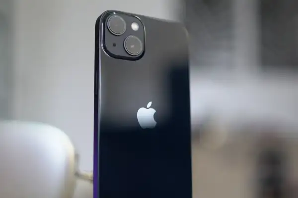 Arrière d'un iPhone 13, avec son logo Apple et le module photo incluant un objectif grand angle.