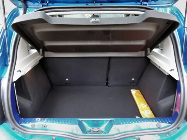 Le coffre d'une Dacia Sandero, vide et propre, prêt à accueillir vos bagages. Un triangle de signalisation jaune est visible sur le côté.