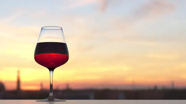 Calice di vino rosso al tramonto, con la sua acidità totale che si percepisce anche visivamente.