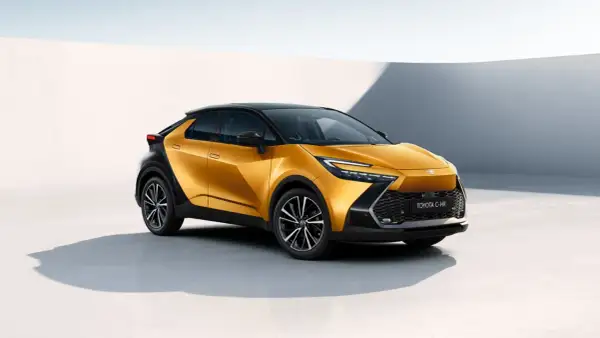 Nowy Toyota C-HR w kolorze złotym, z czarnym dachem i felgami. Zbliżenie na przód auta, widoczna nazwa modelu. Poznaj jego wymiary!