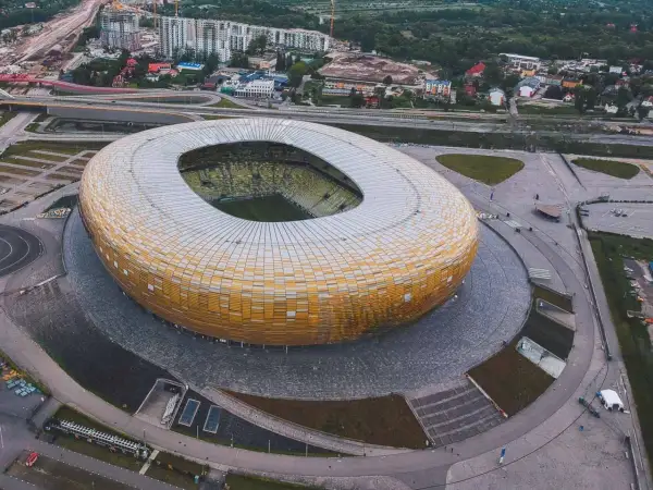 Widok z lotu ptaka na stadion w Gdańsku, z jego charakterystyczną, złotą fasadą. Idealne miejsce na zwiedzanie stadionu gdańsk i poczucie atmosfery wielkich wydarzeń sportowych.
