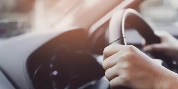 Manos sujetando el volante de un coche, con un ligero ruido al girar el volante.