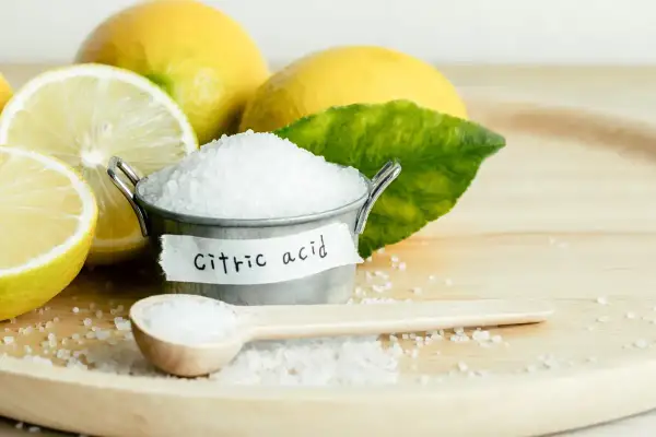 Limoni freschi e un piccolo secchiello con cristalli di acido citrico, che serve per conservare e dare sapore.