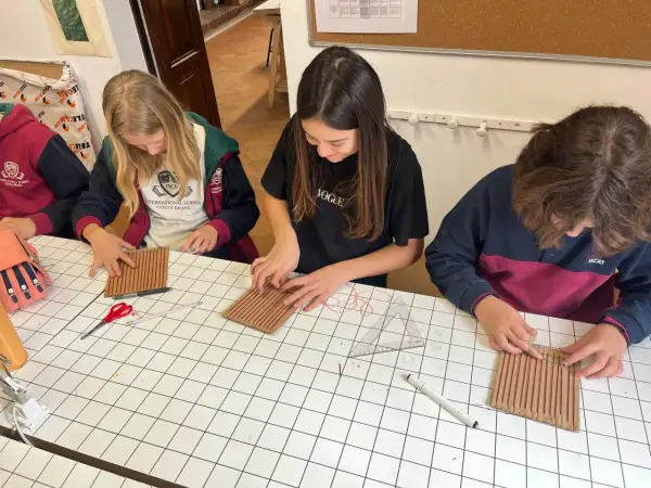 Chicas concentradas en una actividad manual, aprendiendo sobre el IGCSE que es y cómo aplicarlo en proyectos creativos.