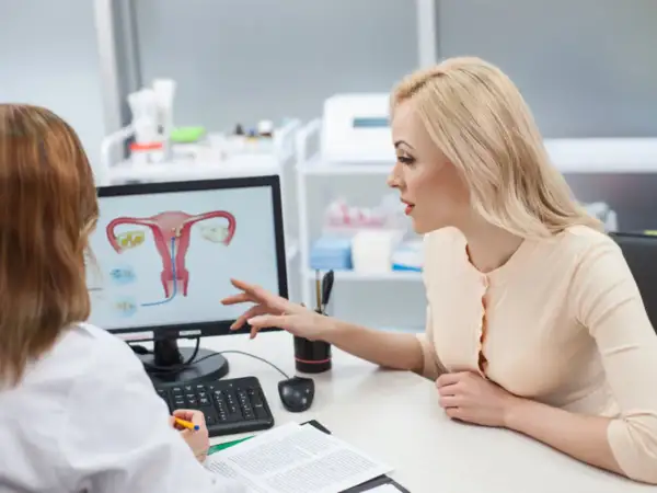 Lekarka omawia z pacjentką budowę macicy i potencjalne problemy, takie jak atonia macicy, wskazując na ekranie.