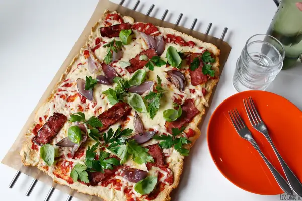 En läcker pizza med bacon och lök, toppad med färska örter och smält ost. Perfekt för en snabb och smakrik måltid.