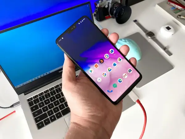 Podłączony do laptopa smartfon, gotowy do transferu danych. Prosty sposób, jak przesłać zdjęcia z telefonu na komputer.